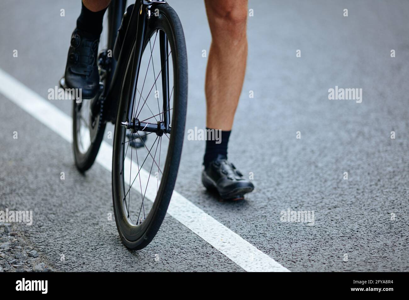 Nahaufnahme der männlichen muskulösen Beine sitzen auf dem Fahrrad im Freien Stockfoto