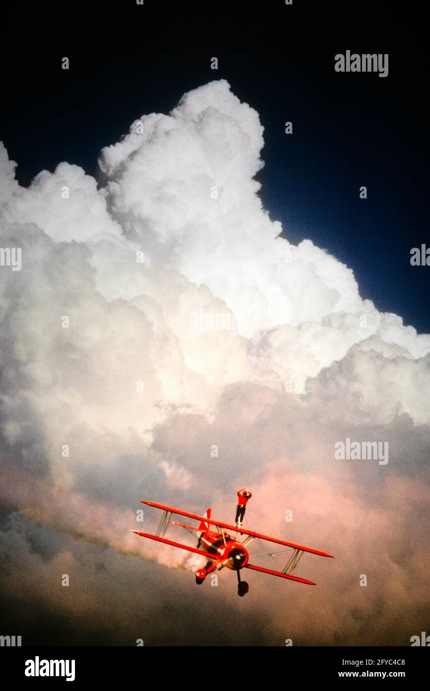 EIN ANONYMER MANN AUS DEN 1990ER JAHREN, EIN WAGHALSIGER WALKER, DER AUF EINEM AUFTRAT DOPPELDECKER FLIEGEN DURCH DRAMATISCHE CUMULUS-WOLKEN - KA7383 GER002 HARS WING BERUF FÄHIGKEITEN ABENTEUER FLUGZEUGE GEFÄHRLICHE PERFORMER STUNT COURAGE KARRIERE ZUSAMMENGESETZTE DRAMATISCHE AUFREGUNG RISKANT STUNTS LUFTFAHRT BESCHÄFTIGUNG ENTERTAINER GEFÄHRLICHE BERUFE FURCHTLOSE GEFAHR UNSICHERE KONZEPTUELLE DRAUFGÄNGER SCHAUSPIELER ATHLETEN WALKER ANONYM ATEMBERAUBEND JEDERWARDY DRAUFGÄNGER ENTERTAINER DARSTELLER ROT WEISS UND BLAU LUFTFAHRT DOPPELDECKER CUMULUS ALTMODISCH Stockfoto