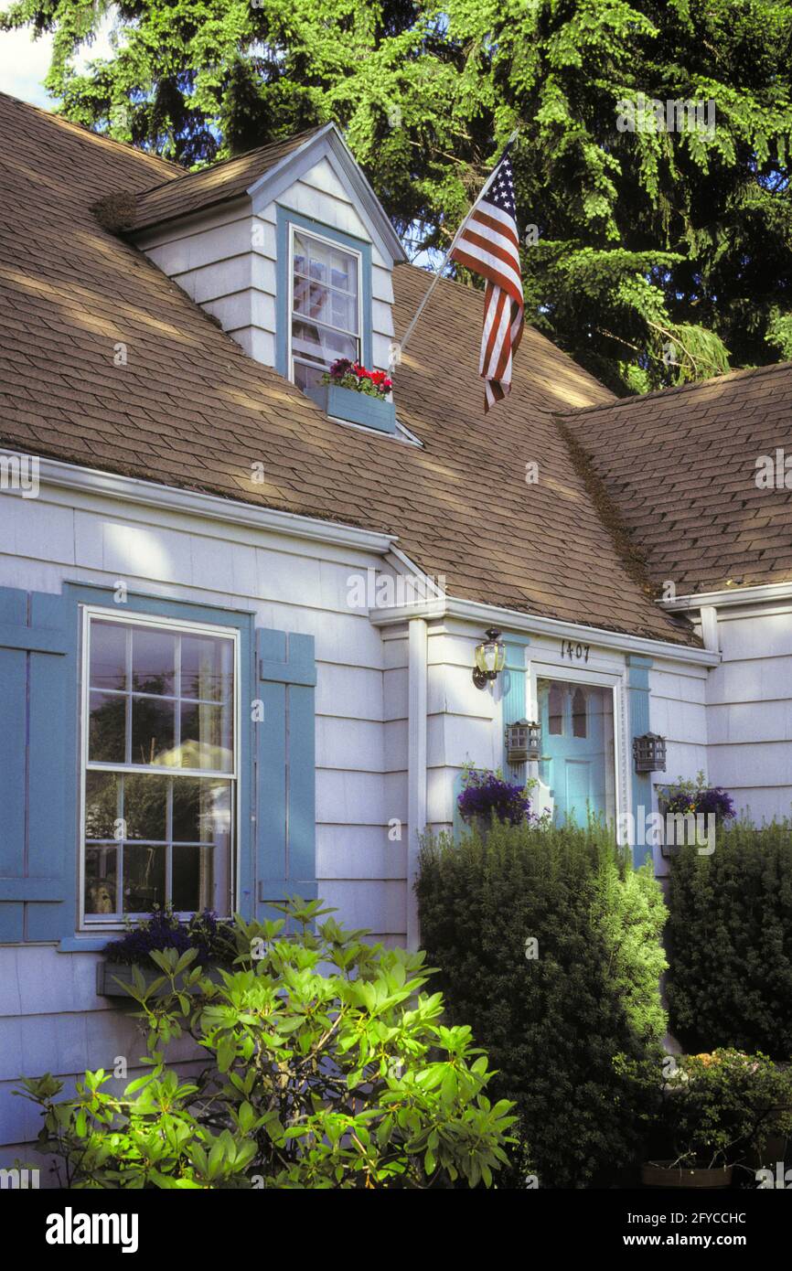 HAUS DER 1990ER JAHRE MIT AMERIKANISCHER FLAGGE, AUSGESTELLT VON DACHGAUBER-WICKLER FÜR PATRIOTISCHER AMERIKANISCHER FEIERTAG - KB30883 LGA001 HARS PATRIOTISCHE RESIDENZ STERNE UND STREIFEN UNTERSTÜTZEN ALTE GLORY CLAPBOARD DACHGAUBE ROT WEISS UND BLAU ANGEZEIGT FEDERAL 4. JULI UNABHÄNGIGKEITSTAG 4. JULI 4. JULI ALTMODISCH Stockfoto