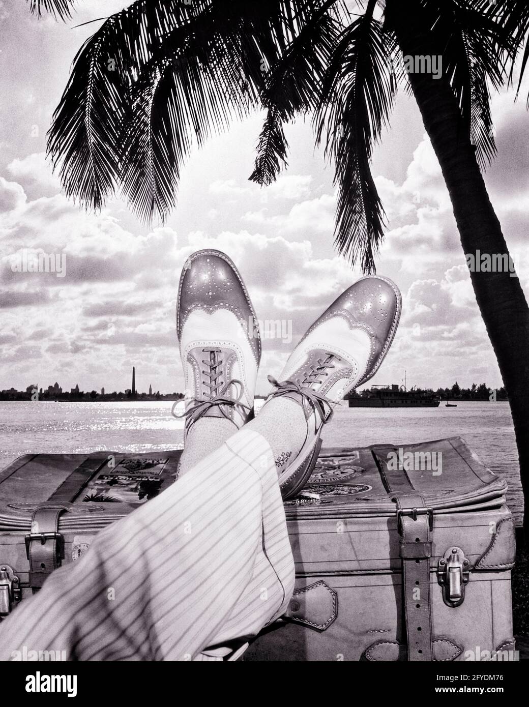 REISENDER AUS DEN 1930ER JAHREN, DER ZWEIFARBIGE ZUSCHAUERSCHUHE MIT FLÜGELSPITZE TRÄGT GESTREIFTE, WEISSE HOSE MIT BÜNDCHEN, DIE AUF DEM KOFFER UNTER DER PALME RUHT - S8543 HAR001 HARS URLAUB FÜR JUNGE ERWACHSENE KREUZTE MODISCH ENTSPANNEND RICH PIECE JOY LIFESTYLE SATISFACTION CELEBRATION STRIPED STUDIO SHOT COPY RAUM PERSONEN MÄNNER GELASSENHEIT VERTRAUEN B & W RUHE ZEIT ABSEITS FLÜGEL HAPPINESS ABENTEUER FREIZEIT SPORTLICHE HOSEN REISE UND KURZURLAUB SCHNÜRSENKEL NIEDRIG WINKEL ERHOLUNG POLIERT AUF URLAUB REISEN KONZEPTIONELLE ZUSCHAUER STILVOLLEN TIPP SPITZEN MIT BÜNDCHEN ZWEIFARBIGE MODE MID-ADULT MID-ADULT MANN ENTSPANNUNG TON ZWEI TON URLAUB FLÜGEL SPITZE FLÜGEL TIPPS Stockfoto