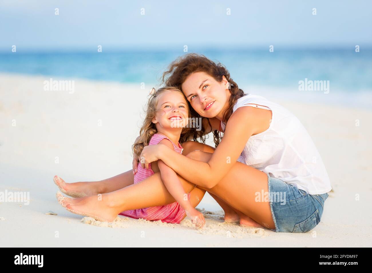 Mutter und kleine Tochter ruhen sich am Strand auf den Malediven aus Im Sommerurlaub Stockfoto