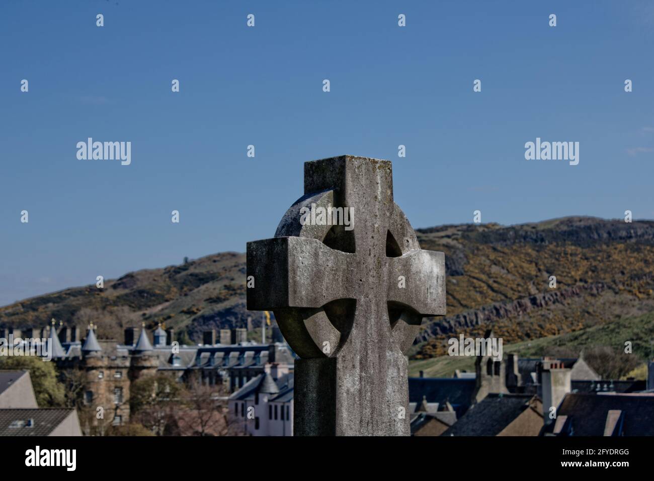 Ein keltisches Kreuzgrab mit Holyrood Palace und Park im Hintergrund, Edinburgh. Stockfoto