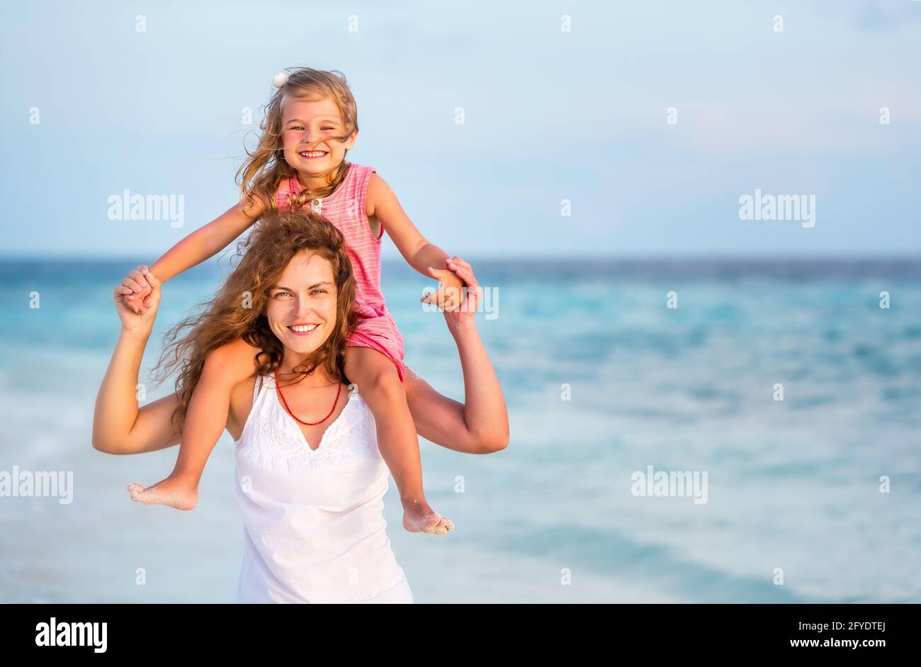 Glückliche Mutter und kleine Tochter, die Spaß am Strand auf den Malediven im Sommerurlaub haben. Familie am Strand Konzept. Stockfoto