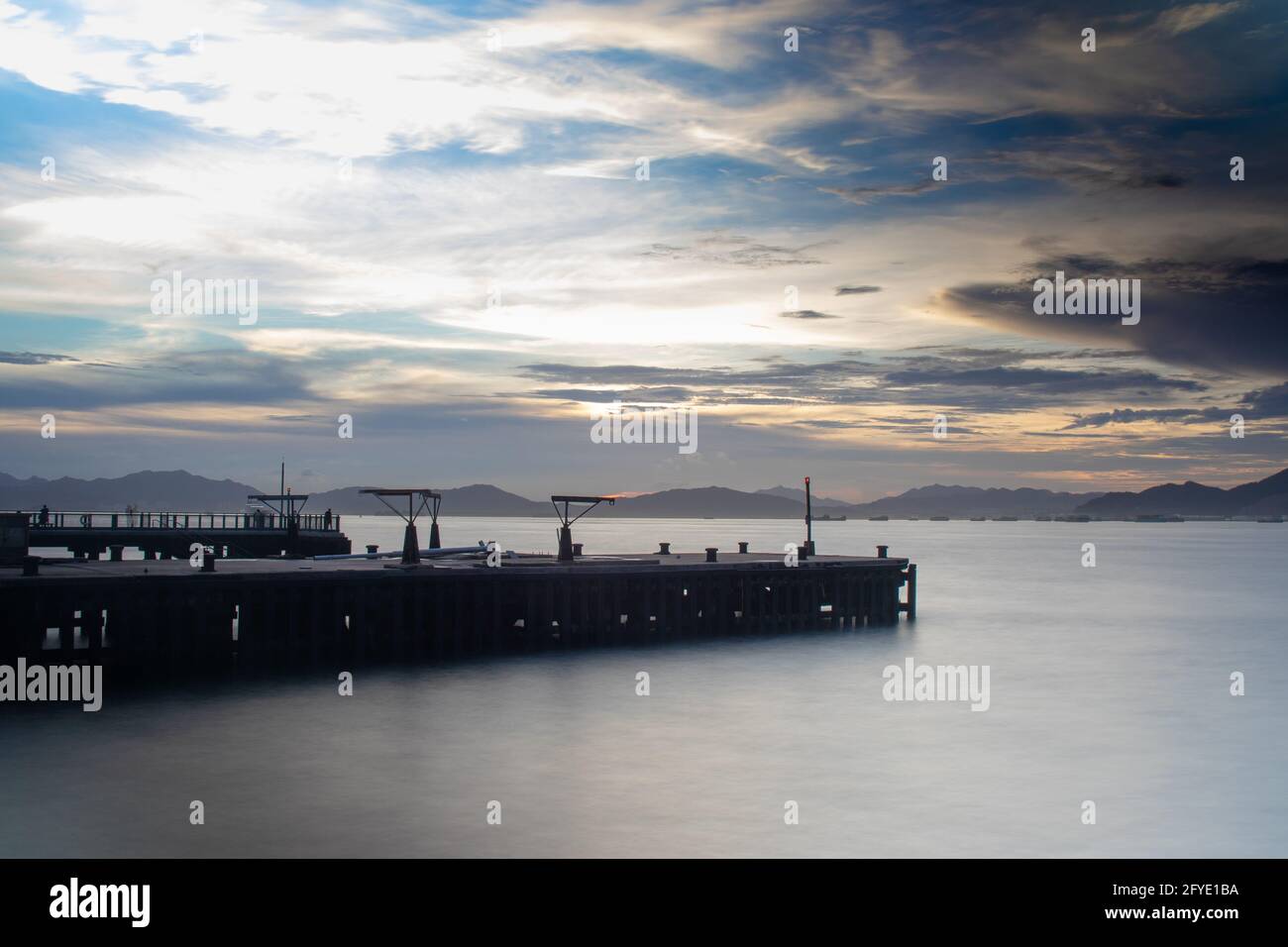 Dramatischer Himmel kurz vor Sonnenuntergang über einem stillvollen Pier an der Strandpromenade in Sheung Wan, Hongkong. Gute Luftqualität trug zur Klarheit bei. Stockfoto