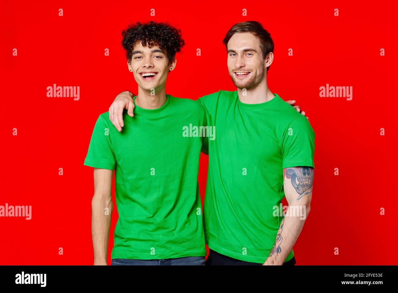 Zwei Freunde umarmen sich in grünen T-Shirts Freundschaftsteam Kommunikation Stockfoto