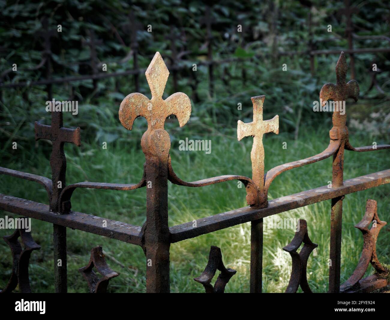 Fleur-de-lys-Emblem und ein Kruzifix aus Schmiedeeisen auf einem Grab, Welwyn, England. Stockfoto