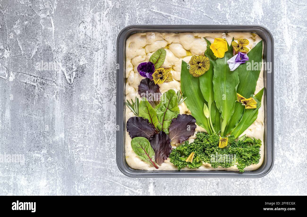 Rohe Blumenmalerei Focaccia, Gartensauerteigkunst mit saisonalen Bärlauch-Blättern. Stockfoto