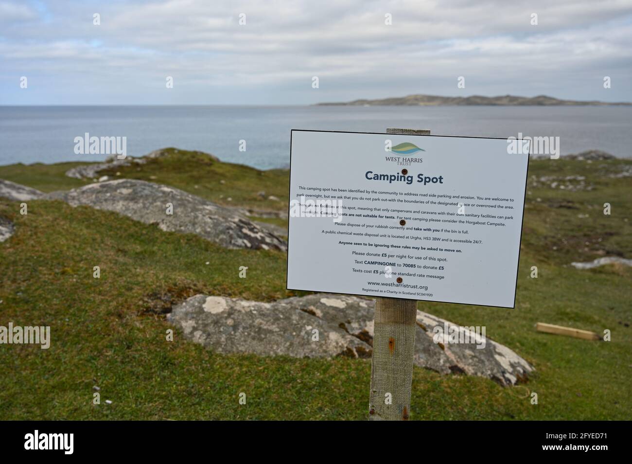 West Harris Trust Campingplatzschild mit Informationen. Verschwommener Hintergrund von Gras, Felsen, Meer und Himmel. Camping-Spots, die auf Straßenrand par Stockfoto