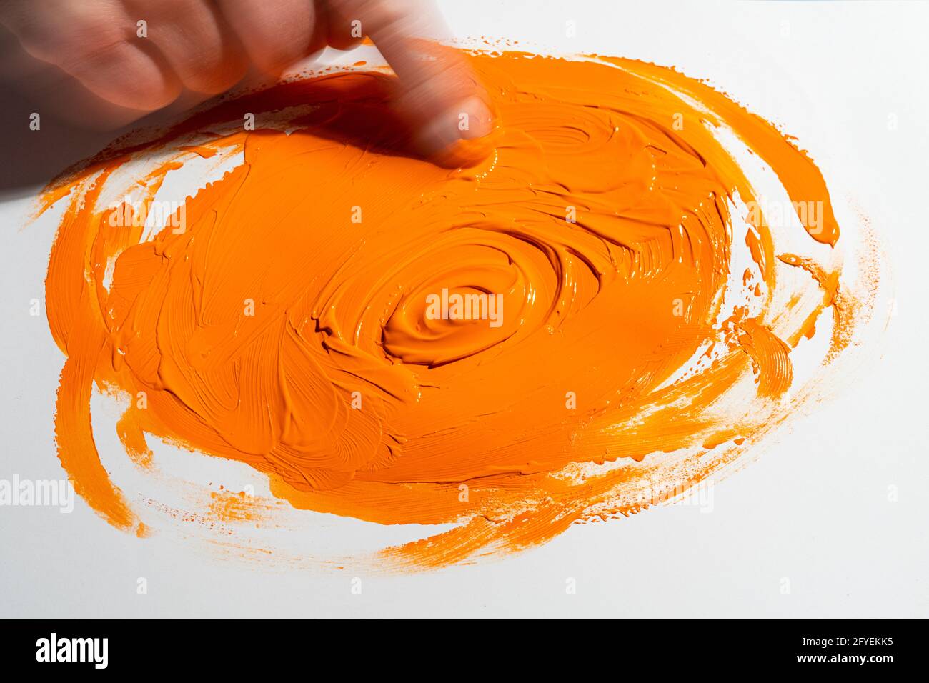 Spreizen Sie mit dem Finger ein orangefarbenes Acrylglas Stockfoto