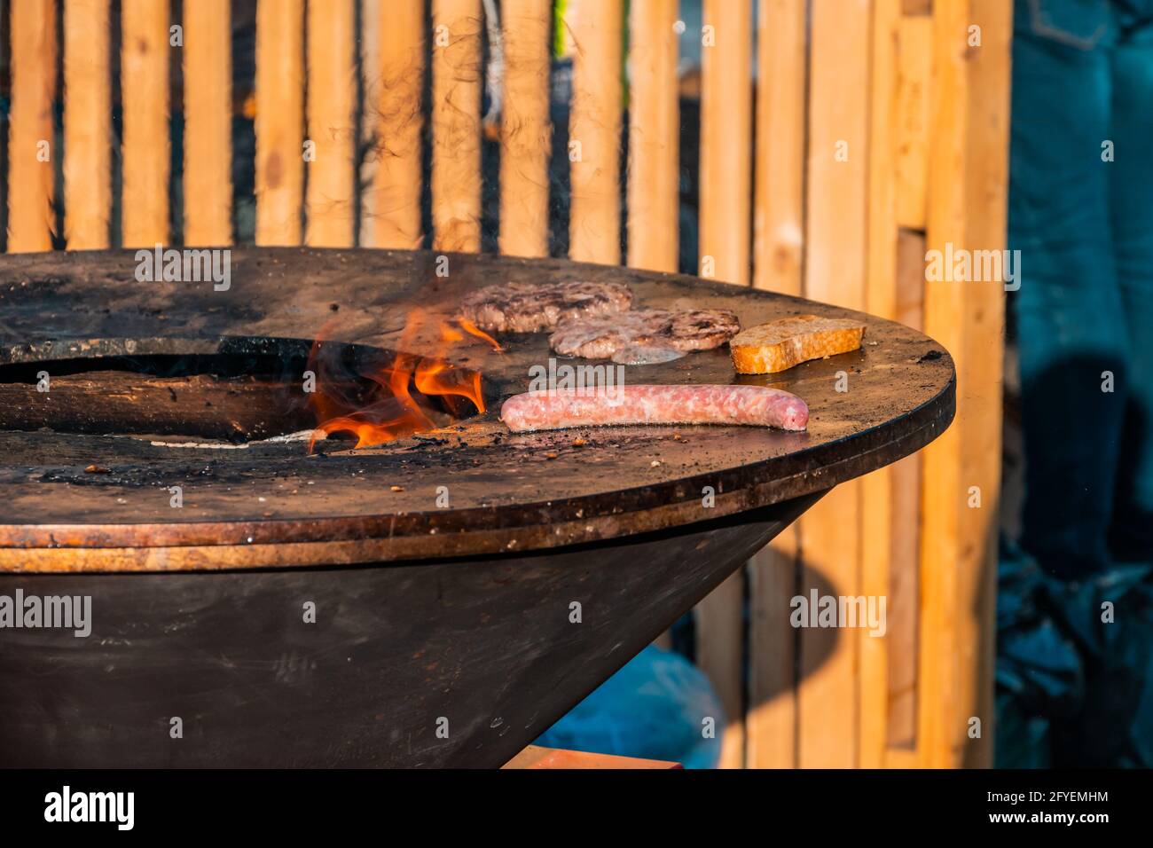 Gegrillte Würstchen, Steaks und Brotscheiben auf einem großen Grill im Freien. Grillfest im Stadtpark. Stockfoto