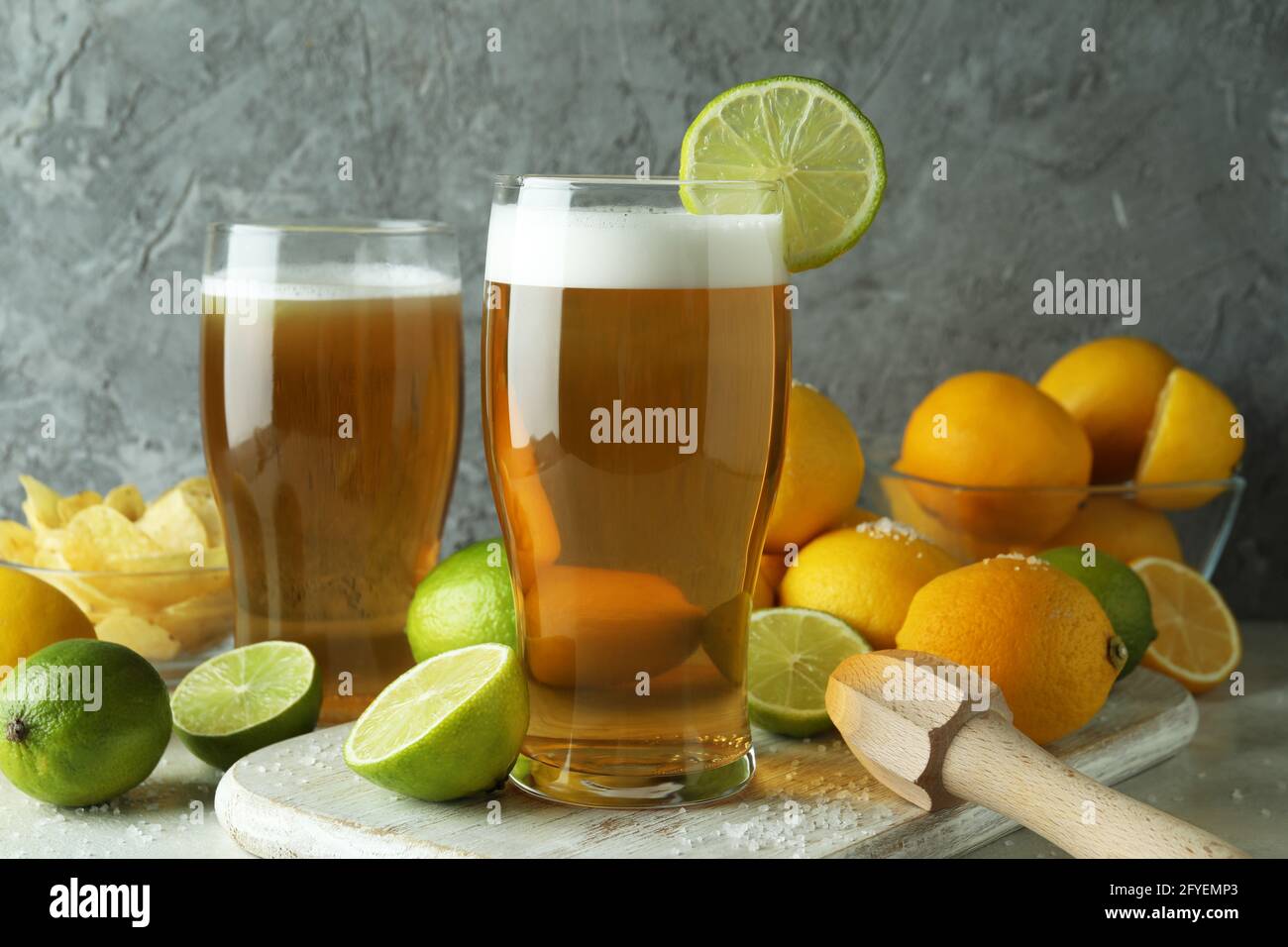 Bier mit Zitrusfrüchten vor grauem strukturiertem Hintergrund Stockfoto