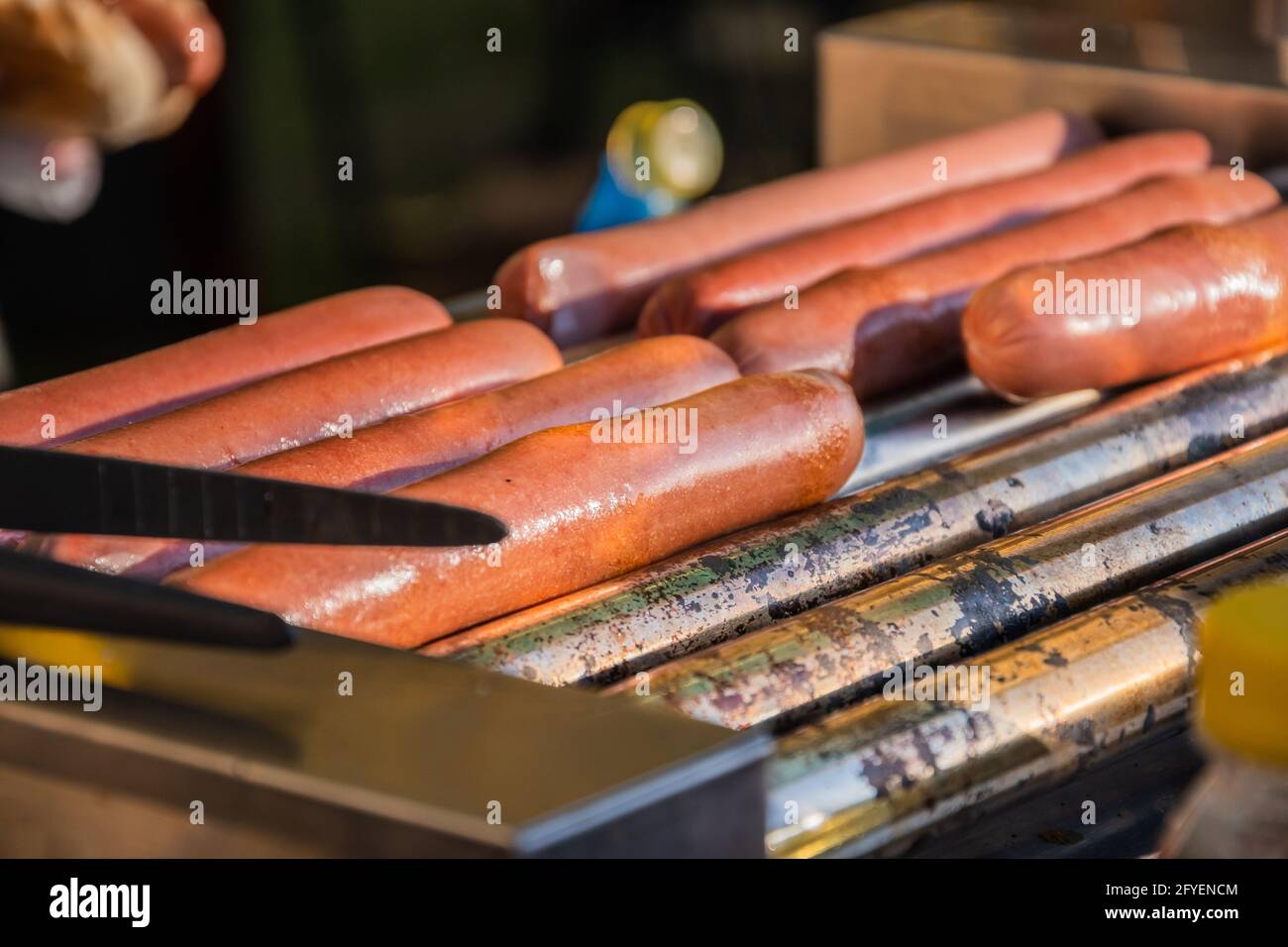 Hot Dog Würstchen werden auf einer rotierenden Kochmaschine gebraten In einem Café im Freien Stockfoto