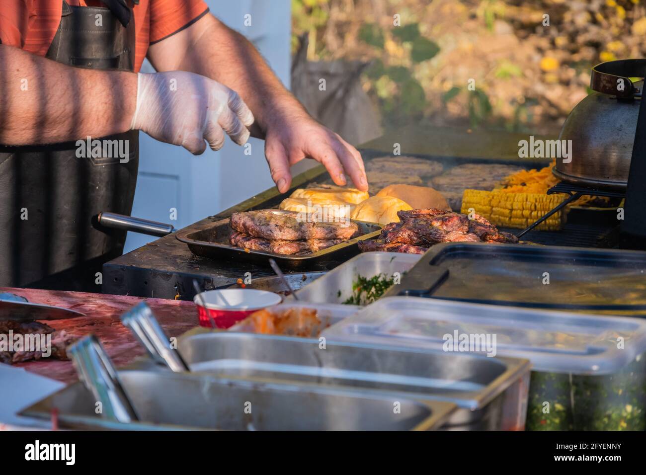 Kochen eines Burger aus den Zutaten. Ein professioneller Koch bereitet einen Burger zu. Grillfest im Stadtpark. Street Fast Food. Stockfoto