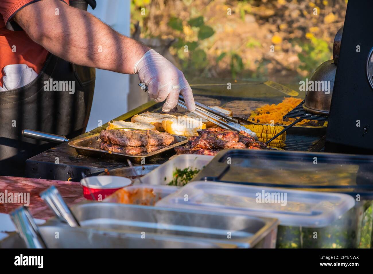 Kochen eines Burger aus den Zutaten. Ein professioneller Koch bereitet einen Burger zu. Grillfest im Stadtpark. Street Fast Food. Stockfoto