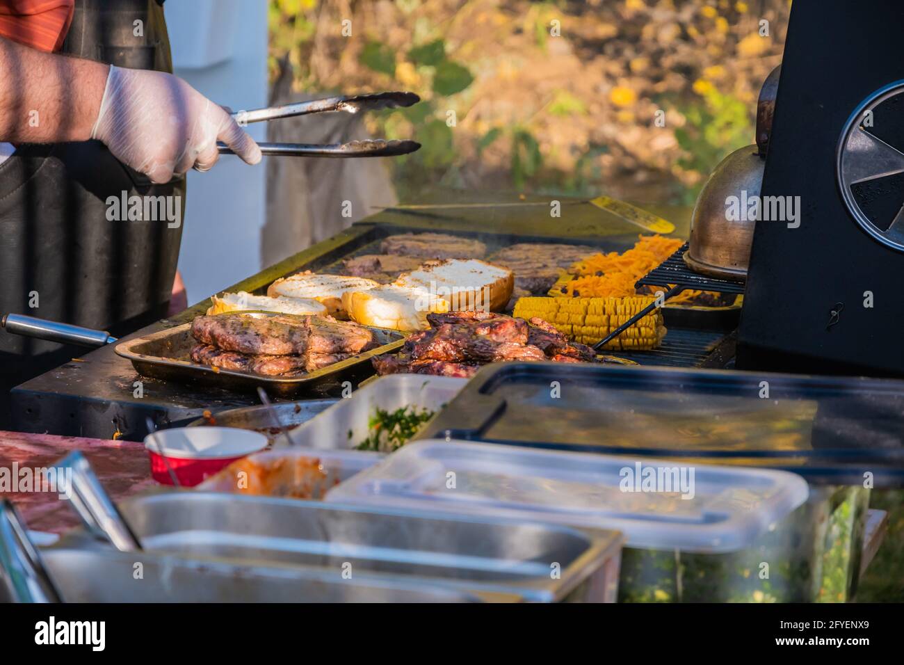 Kochen eines Burger aus den Zutaten. Ein professioneller Koch bereitet einen Burger zu. Grillfest im Stadtpark. Street Fast Food. Stockfoto
