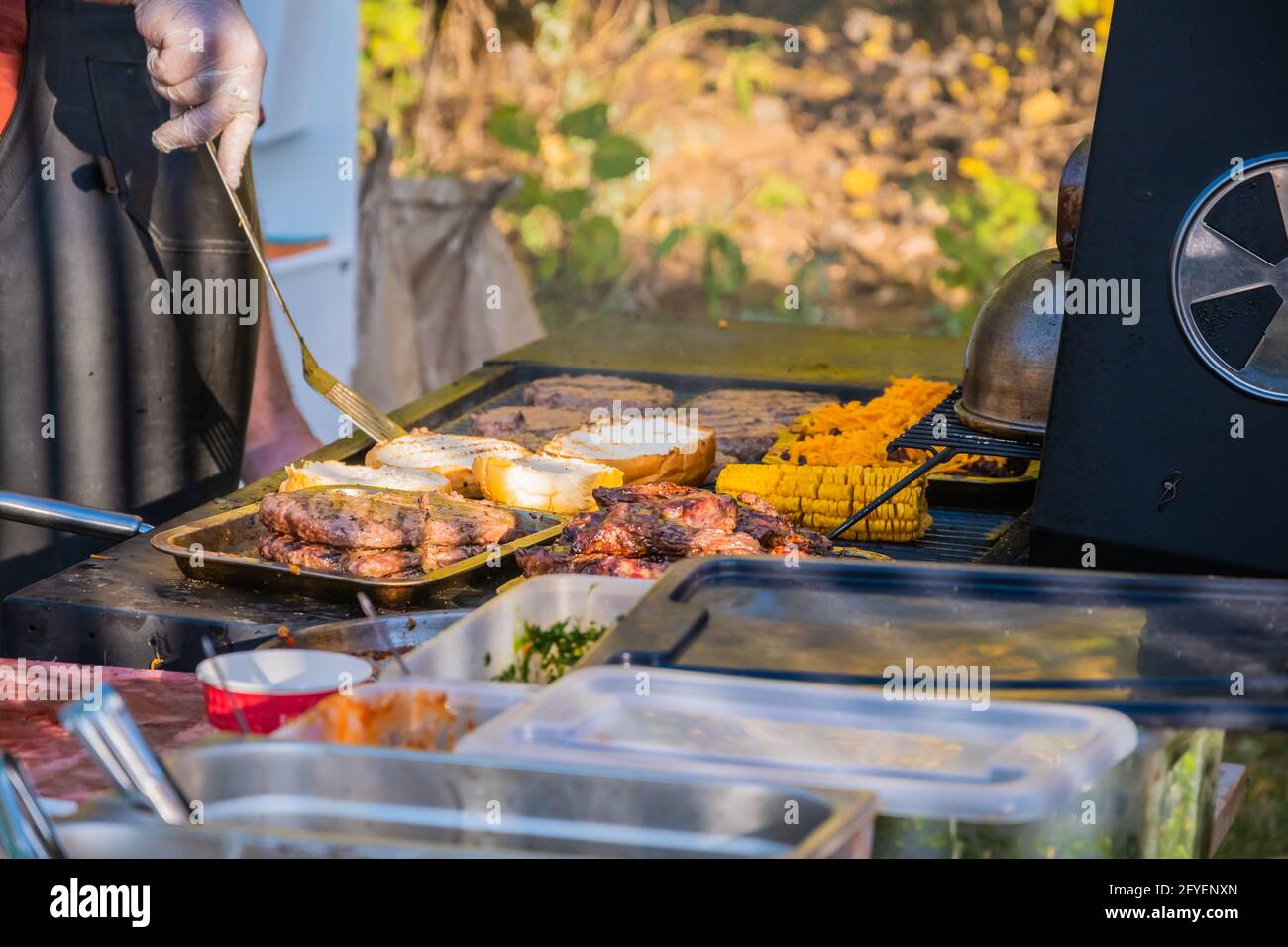 Kochen eines Burger aus den Zutaten. Ein professioneller Koch bereitet einen Burger zu. Grillfest im Stadtpark. Street Fast Food. Stockfoto