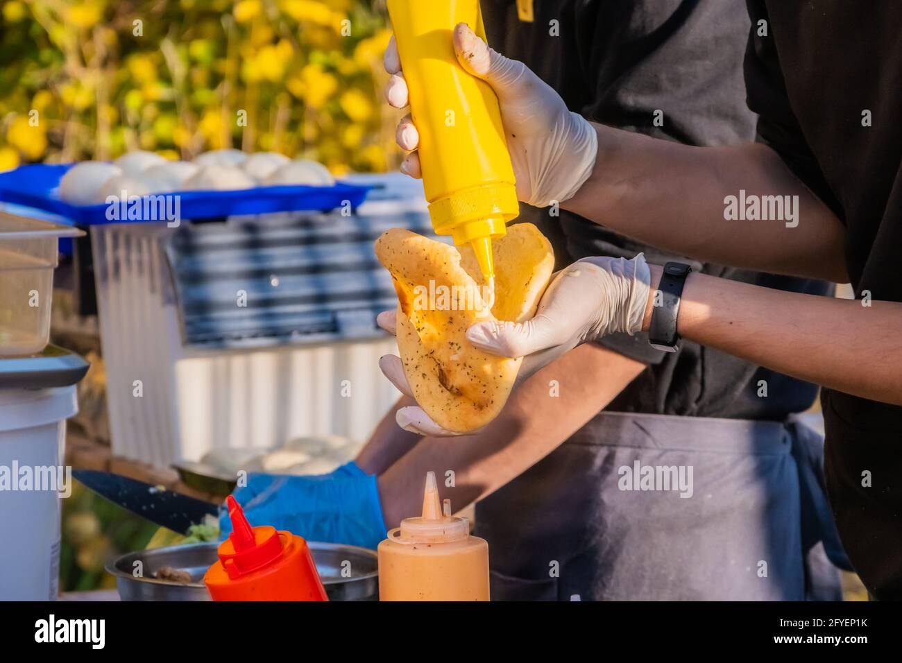 Ein professioneller Koch füllt die Pita mit Füllung. Grillfest im Stadtpark. Street Fast Food. Stockfoto