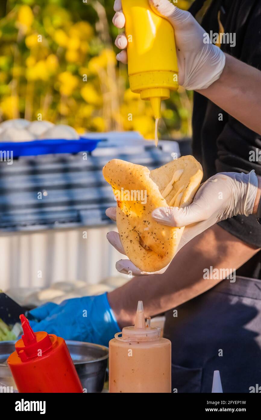 Ein professioneller Koch füllt die Pita mit Füllung. Grillfest im Stadtpark. Street Fast Food. Stockfoto