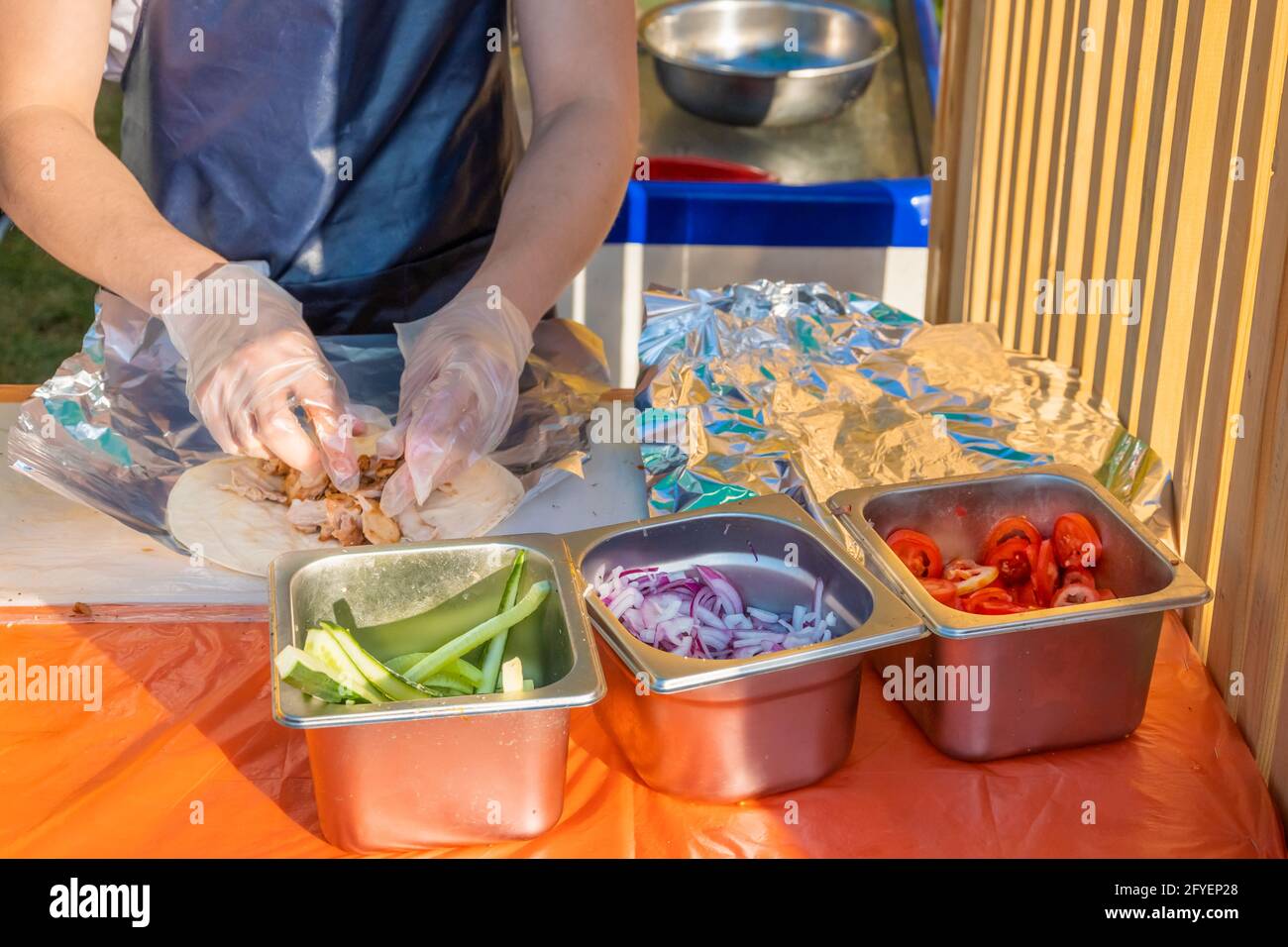 Ein professioneller Koch füllt die Gyros mit Füllung. Grillfest im Stadtpark. Griechische Küche, Street Fast Food. Stockfoto