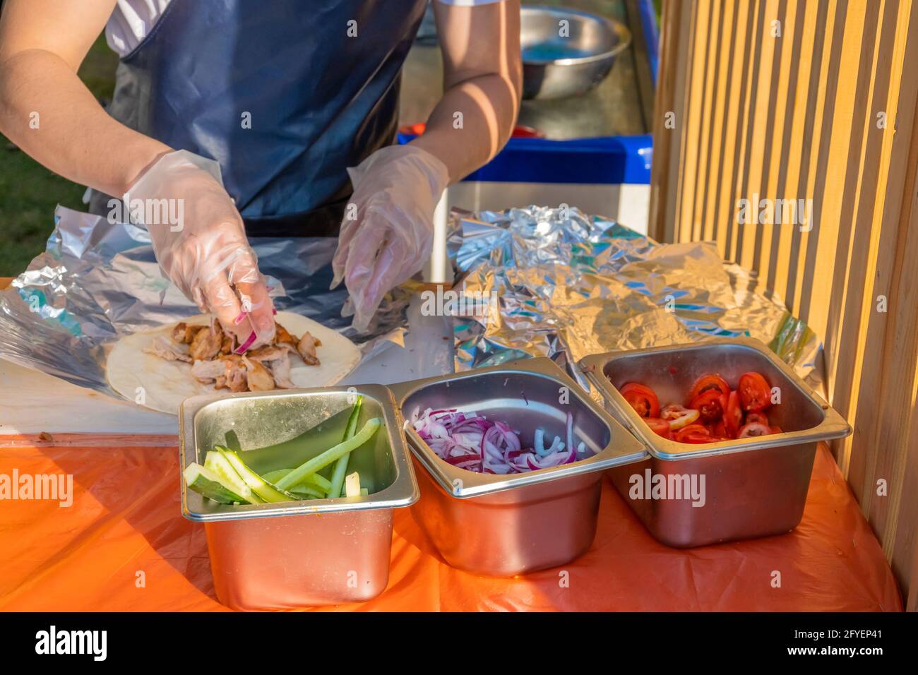 Ein professioneller Koch füllt die Gyros mit Füllung. Grillfest im Stadtpark. Griechische Küche, Street Fast Food. Stockfoto