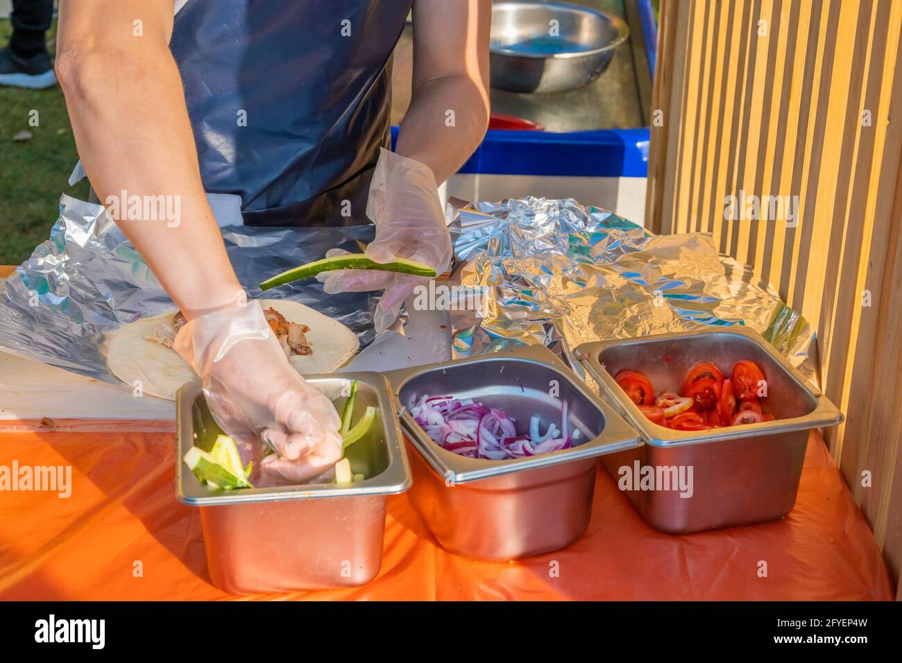 Ein professioneller Koch füllt die Gyros mit Füllung. Grillfest im Stadtpark. Griechische Küche, Street Fast Food. Stockfoto