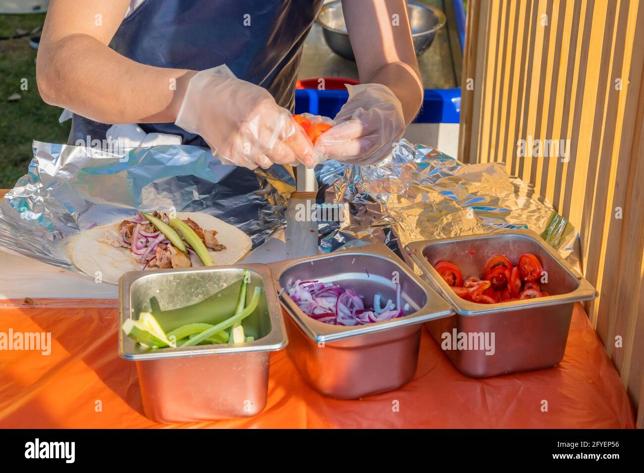Ein professioneller Koch füllt die Gyros mit Füllung. Grillfest im Stadtpark. Griechische Küche, Street Fast Food. Stockfoto