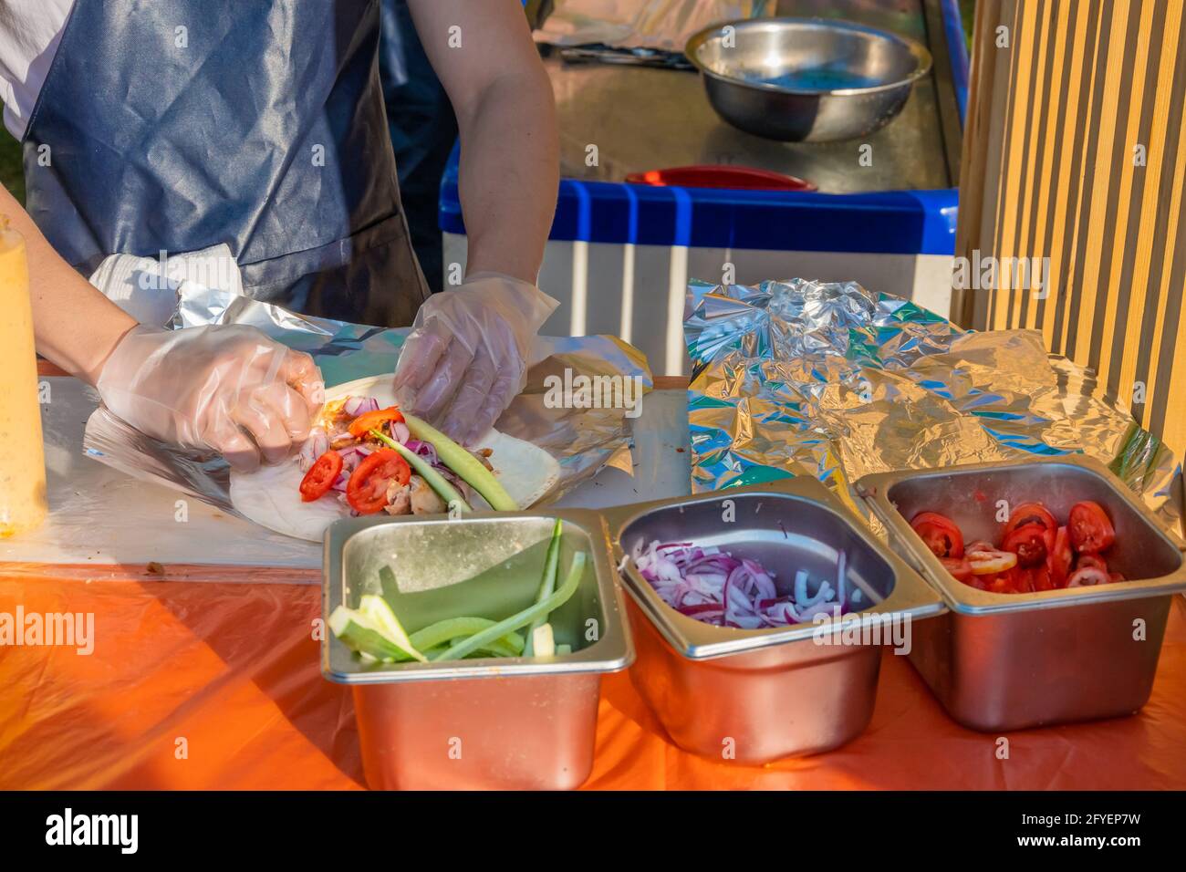 Ein professioneller Koch füllt die Gyros mit Füllung. Grillfest im Stadtpark. Griechische Küche, Street Fast Food. Stockfoto