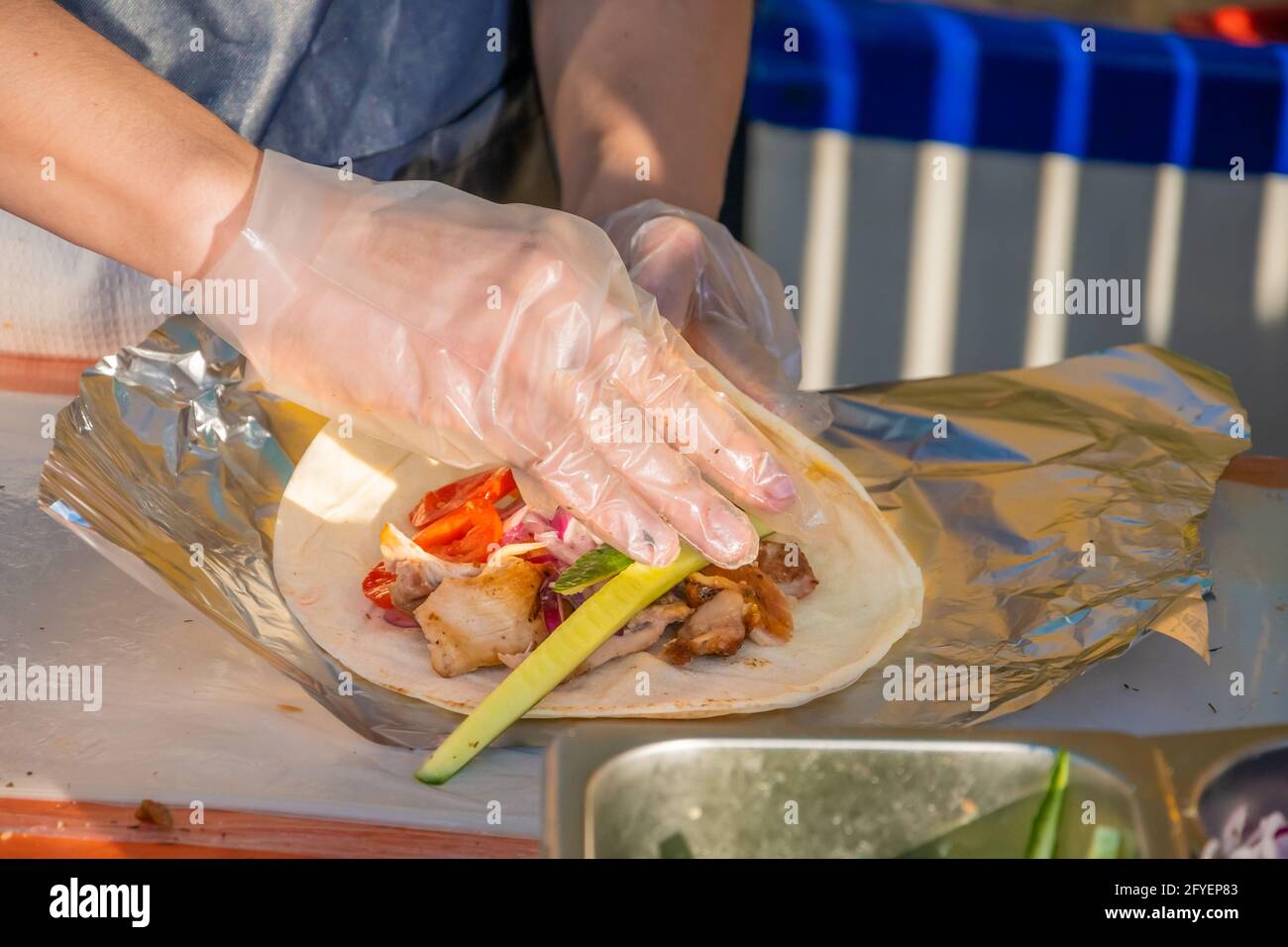 Ein professioneller Koch füllt die Gyros mit Füllung. Grillfest im Stadtpark. Griechische Küche, Street Fast Food. Stockfoto