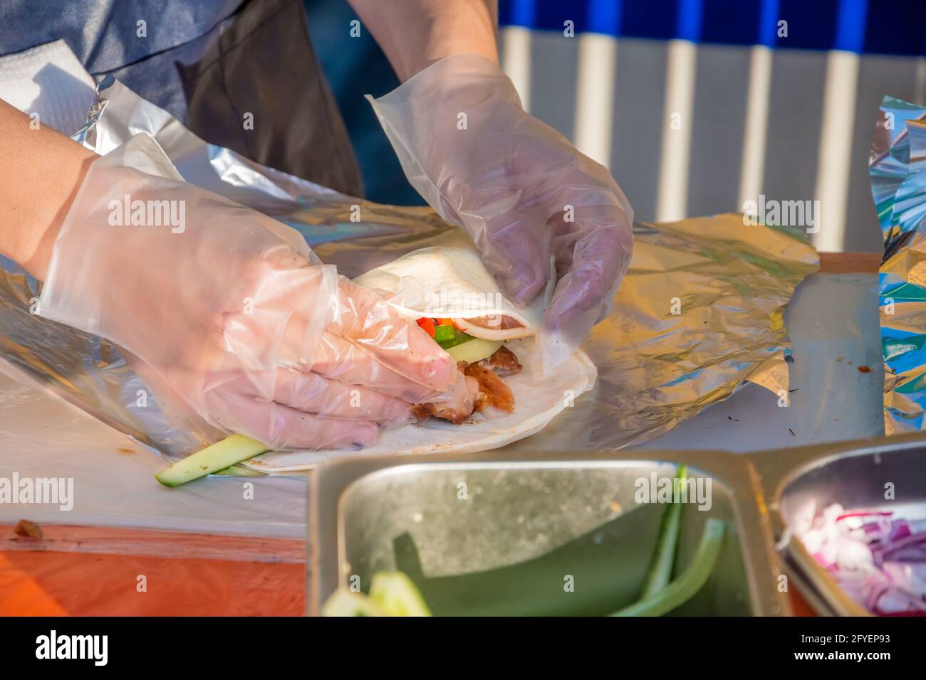Ein professioneller Koch füllt die Gyros mit Füllung. Grillfest im Stadtpark. Griechische Küche, Street Fast Food. Stockfoto
