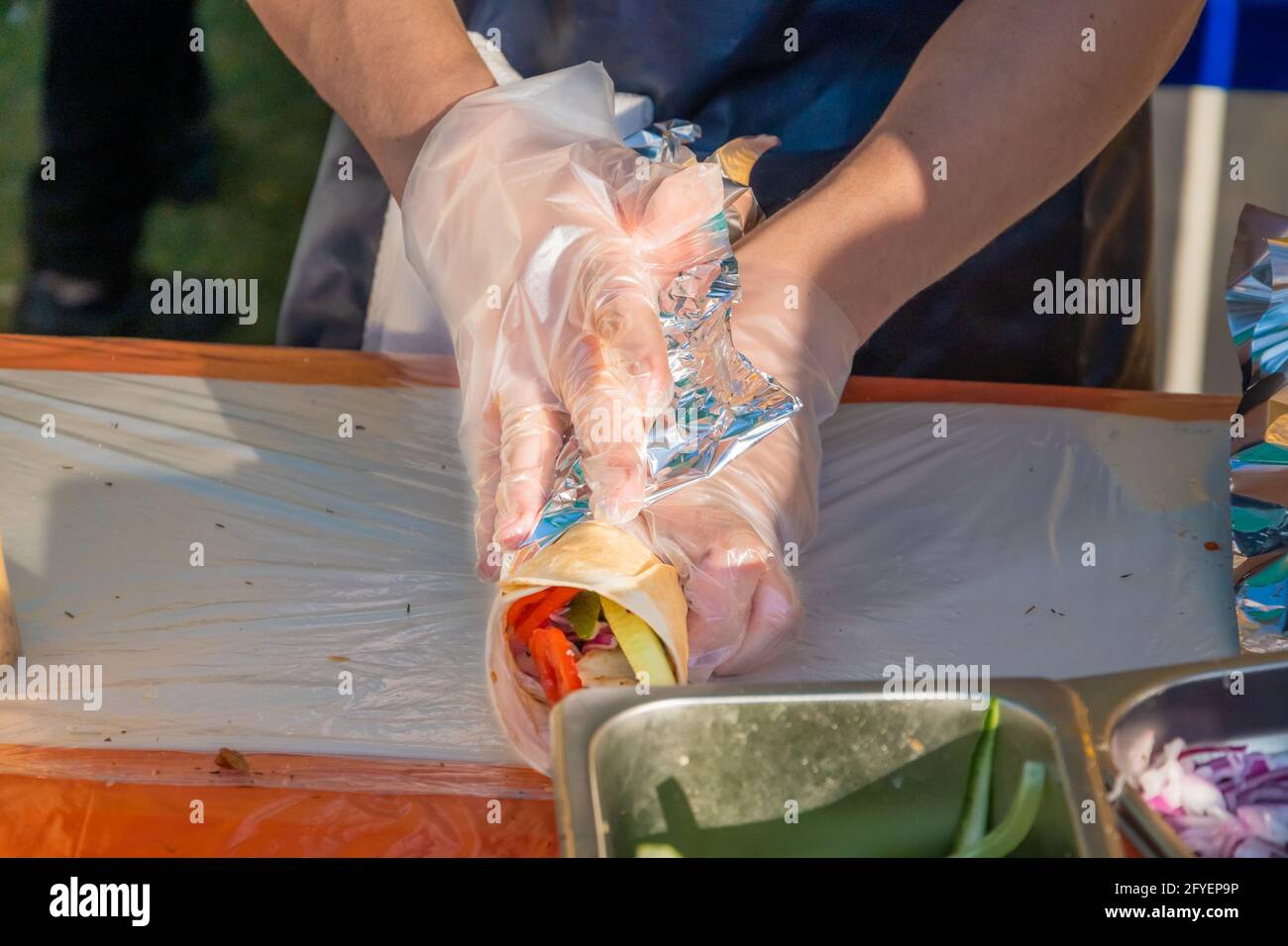 Ein professioneller Koch füllt die Gyros mit Füllung. Grillfest im Stadtpark. Griechische Küche, Street Fast Food. Stockfoto