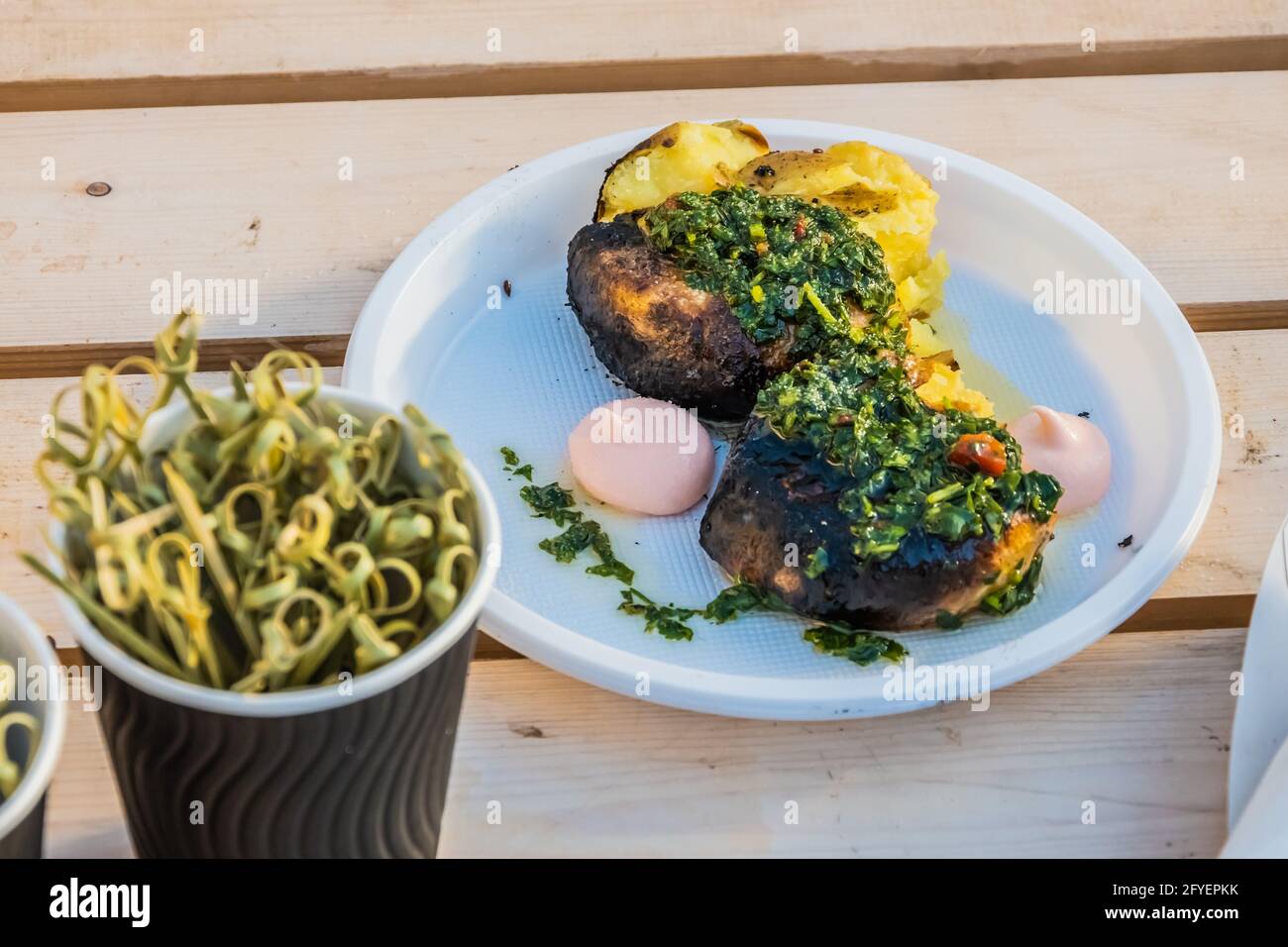 Vegetarische Küche – heiße, gebackene Kartoffelscheiben, die mit Kräutern und Gewürzen bedeckt sind, auf der Theke eines Straßenverkäufers. Food Festival im Stadtpark. Street fas Stockfoto