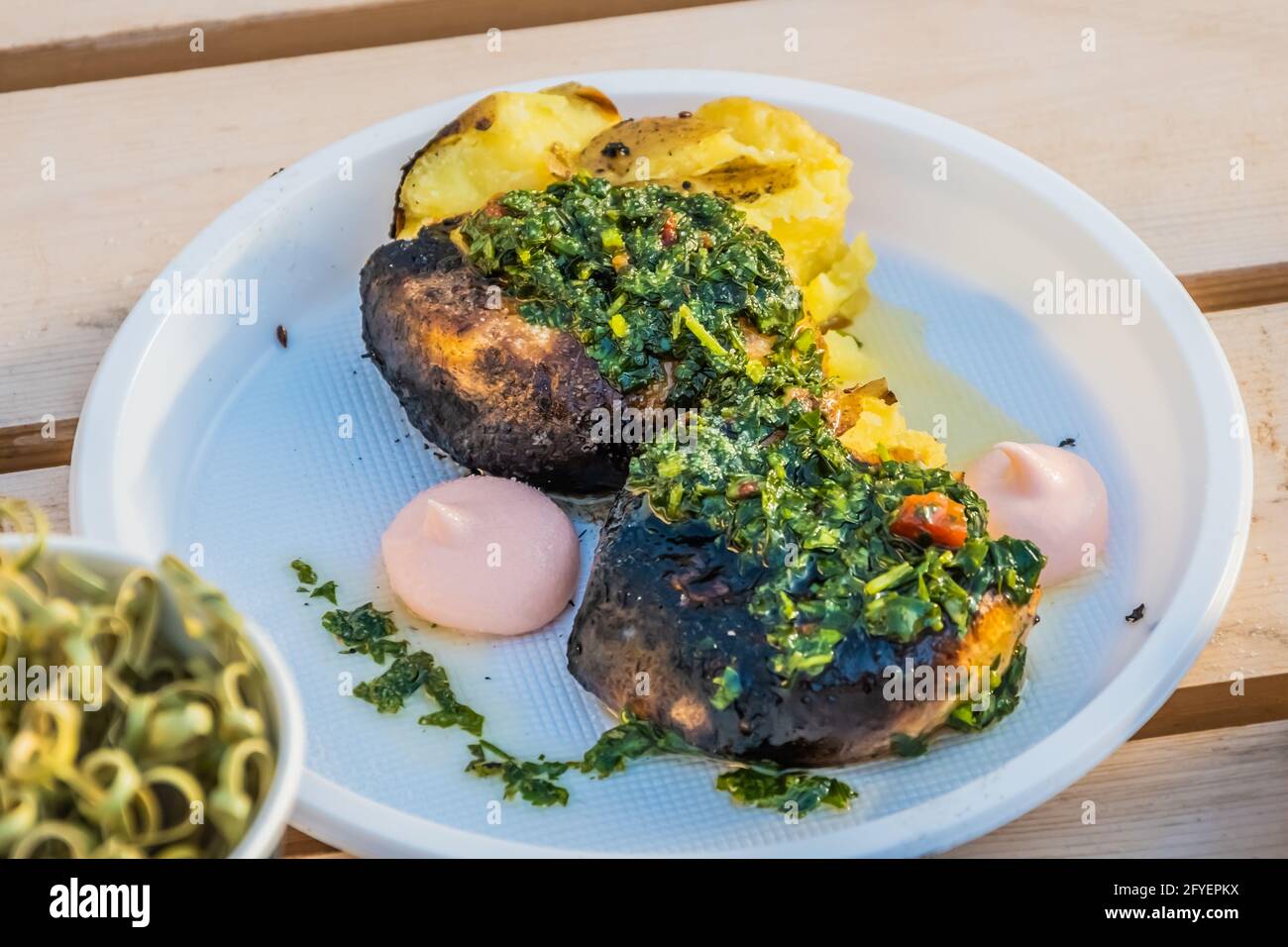 Vegetarische Küche – heiße, gebackene Kartoffelscheiben, die mit Kräutern und Gewürzen bedeckt sind, auf der Theke eines Straßenverkäufers. Food Festival im Stadtpark. Street fas Stockfoto