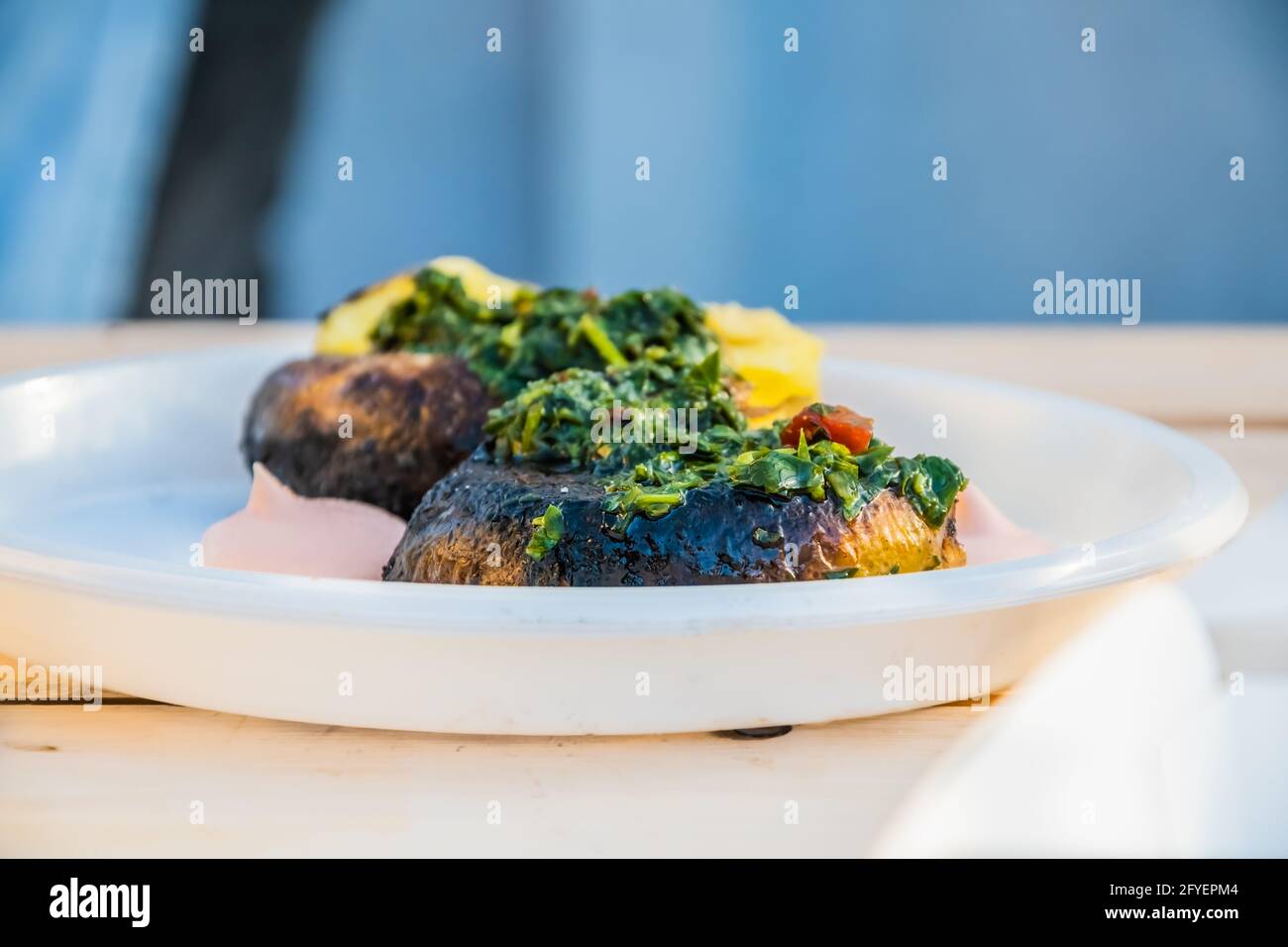 Vegetarische Küche – heiße, gebackene Kartoffelscheiben, die mit Kräutern und Gewürzen bedeckt sind, auf der Theke eines Straßenverkäufers. Food Festival im Stadtpark. Street fas Stockfoto