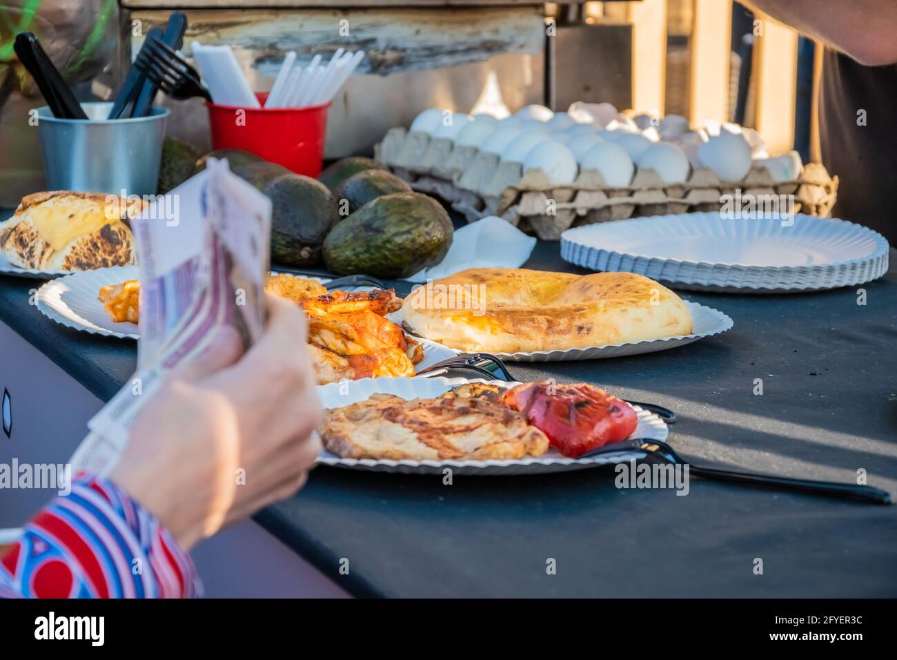 Aus der Nähe einer Frau mit einer Papierwährung bestellt ein Kunde am Schalter eines mexikanischen Restaurants unter freiem Himmel. Food Festival in Th Stockfoto