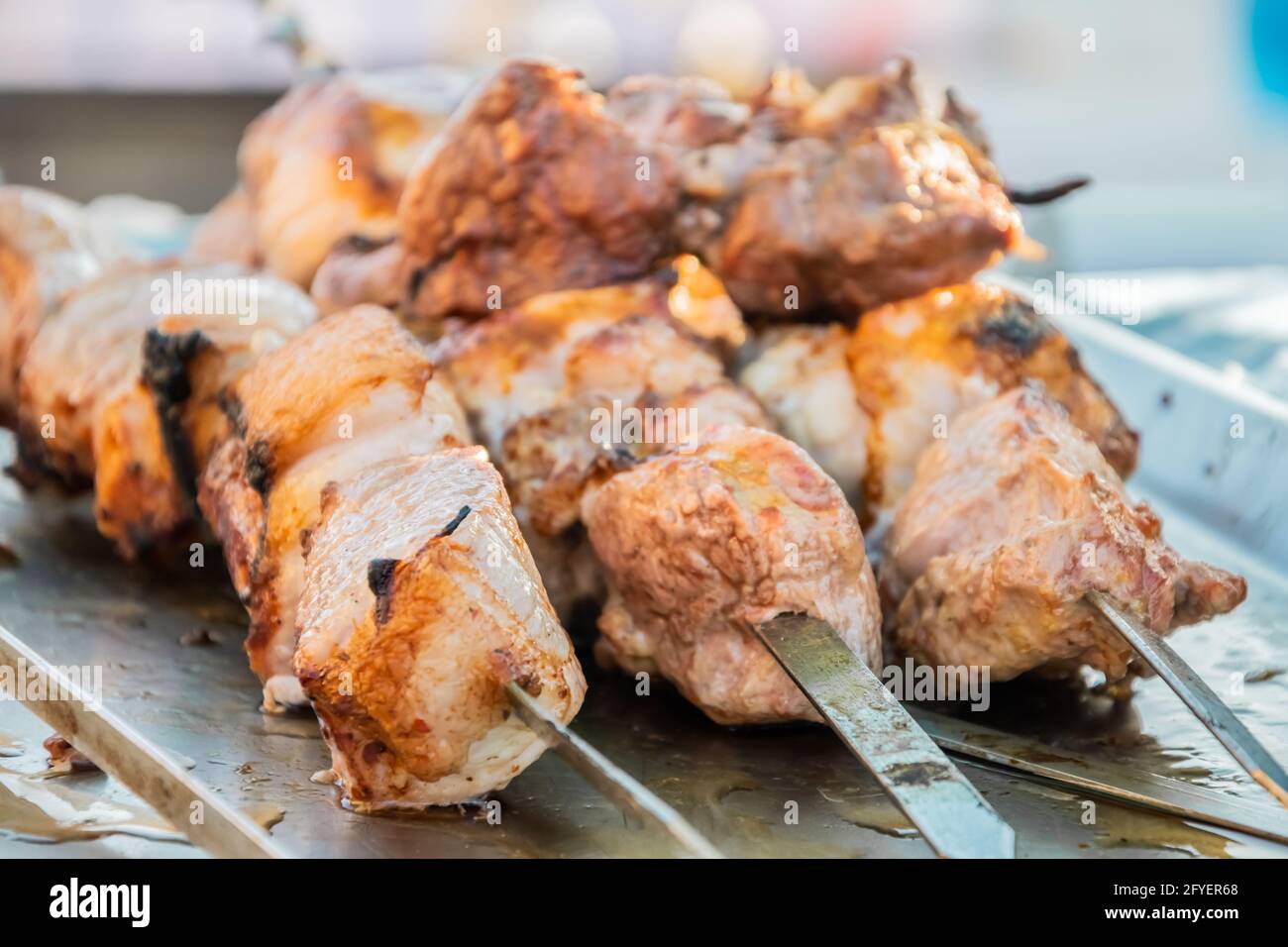 Gebratener Shish Kebab auf Spiessen an der Theke eines Straßenrestaurants. Food Festival im Stadtpark. Street Fast Food. Selektiver Fokus, geringe Tiefe o Stockfoto
