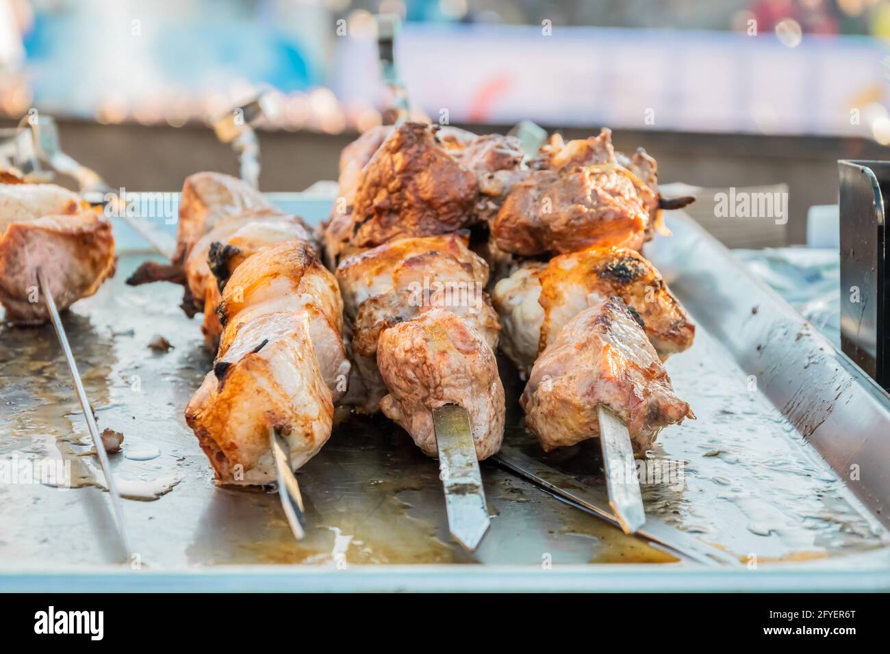 Gebratener Shish Kebab auf Spiessen an der Theke eines Straßenrestaurants. Food Festival im Stadtpark. Street Fast Food. Selektiver Fokus, geringe Tiefe o Stockfoto