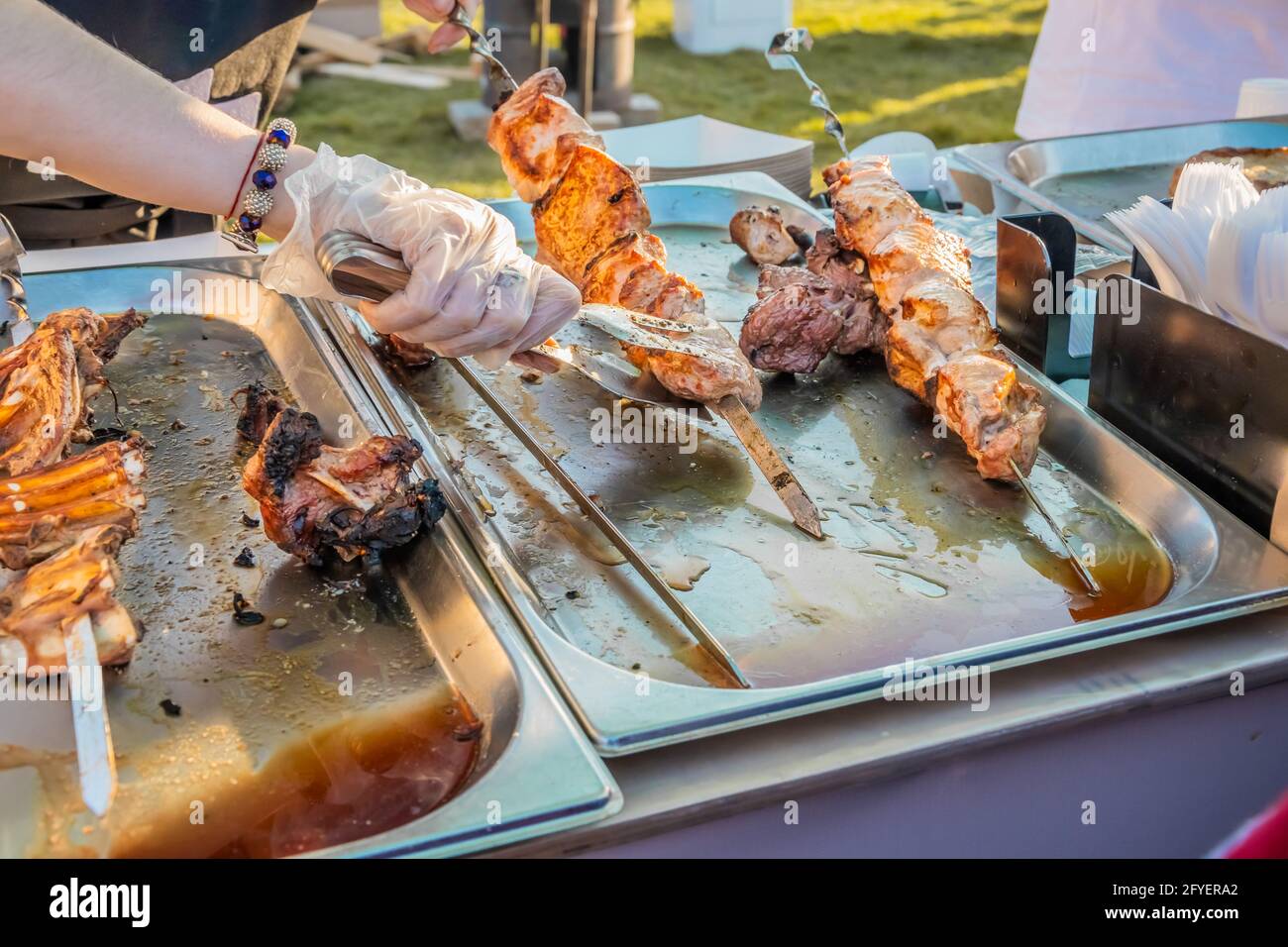 Gebratener Shish Kebab auf Spiessen an der Theke eines Straßenrestaurants. Food Festival im Stadtpark. Street Fast Food. Selektiver Fokus, geringe Tiefe o Stockfoto