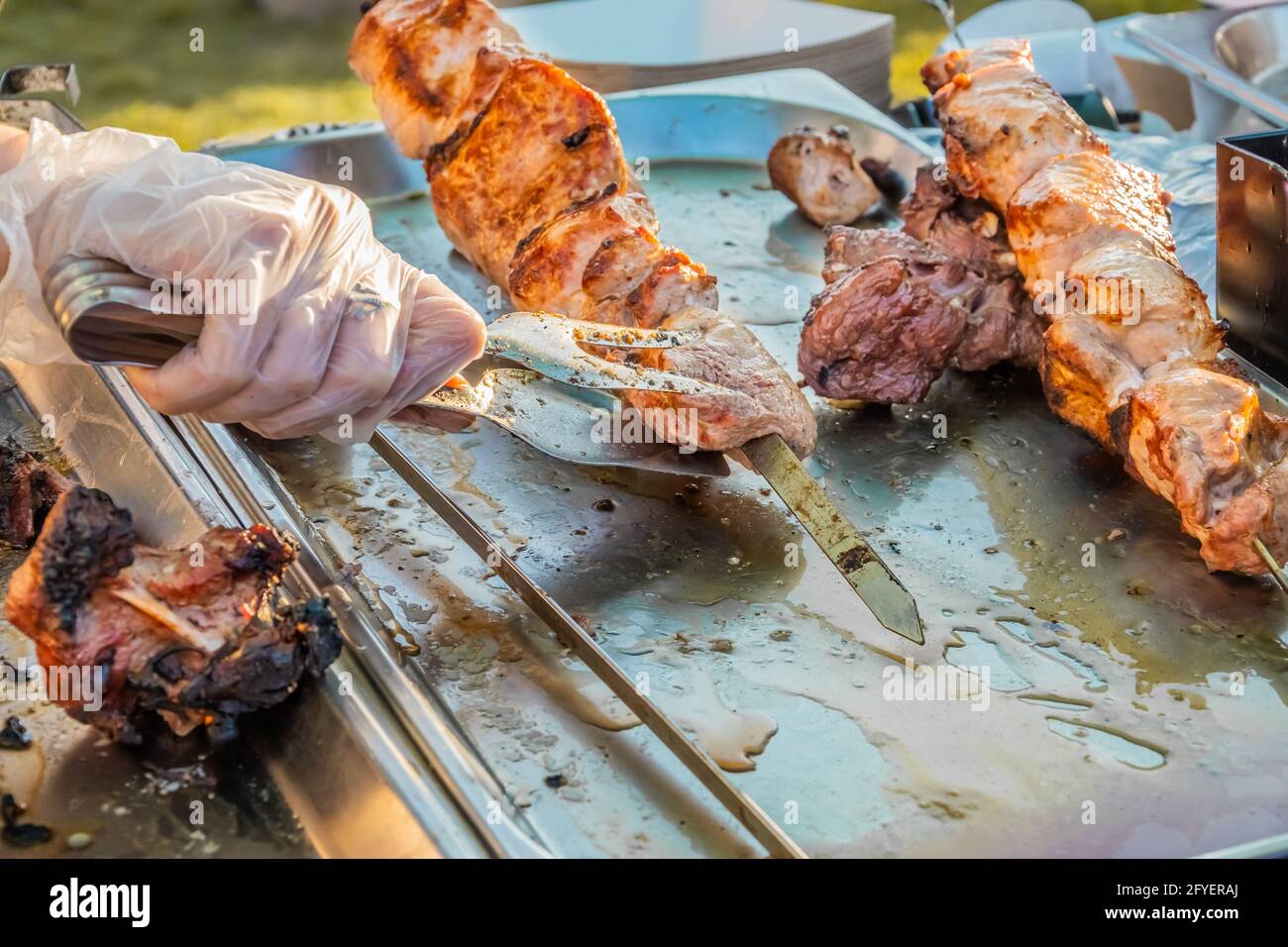 Gebratener Shish Kebab auf Spiessen an der Theke eines Straßenrestaurants. Food Festival im Stadtpark. Street Fast Food. Selektiver Fokus, geringe Tiefe o Stockfoto