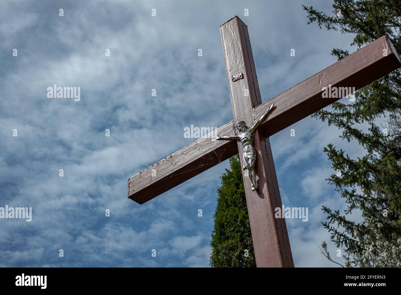 Metallkreuz mit Jesus auf einem Hintergrund von Wolken. Religiöses Thema. Stockfoto