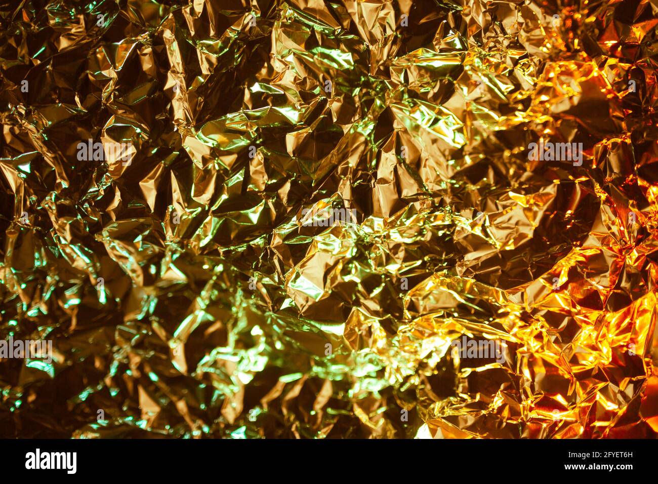 Metall-Folienpapier zerknittert. Hintergrund mit Chrome-Textur. Abstrakter metallischer Hintergrund mit goldenen und grünen Smaragdtönen mit rauer Textur. Überlegene ric Stockfoto