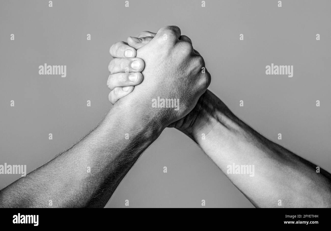 Freundlicher Händedruck, Freundschaftsgrüße, Teamarbeit, Freundschaft. Handschlag, Waffen, Freundschaft. Vergleich der Handrivalität mit der Herausforderung. Stockfoto