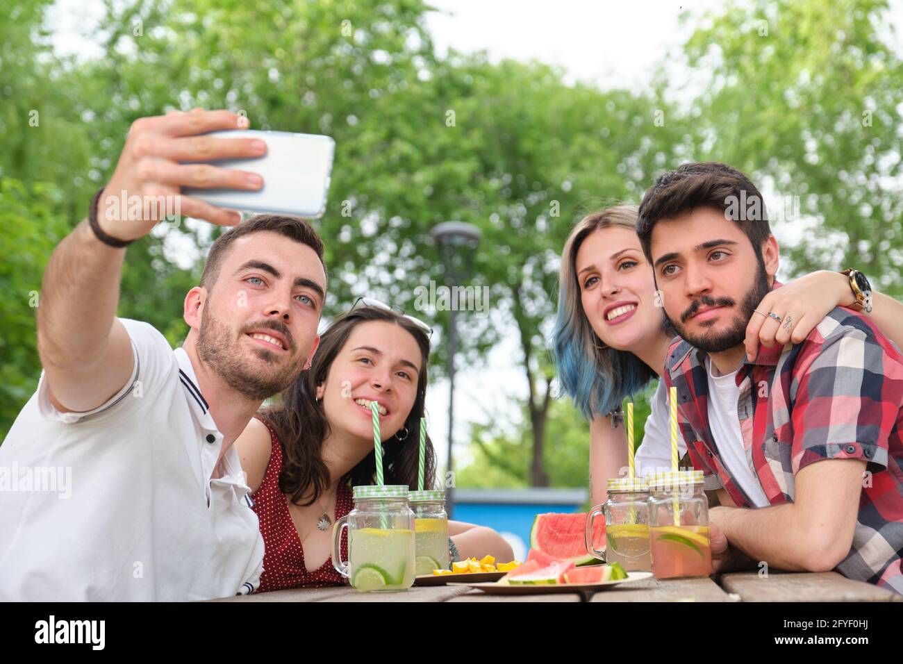 Eine Gruppe von glücklichen Freunden, die ein Selfie machen und Spaß in einem Park haben. Picknick an einem sonnigen Sommertag. Stockfoto