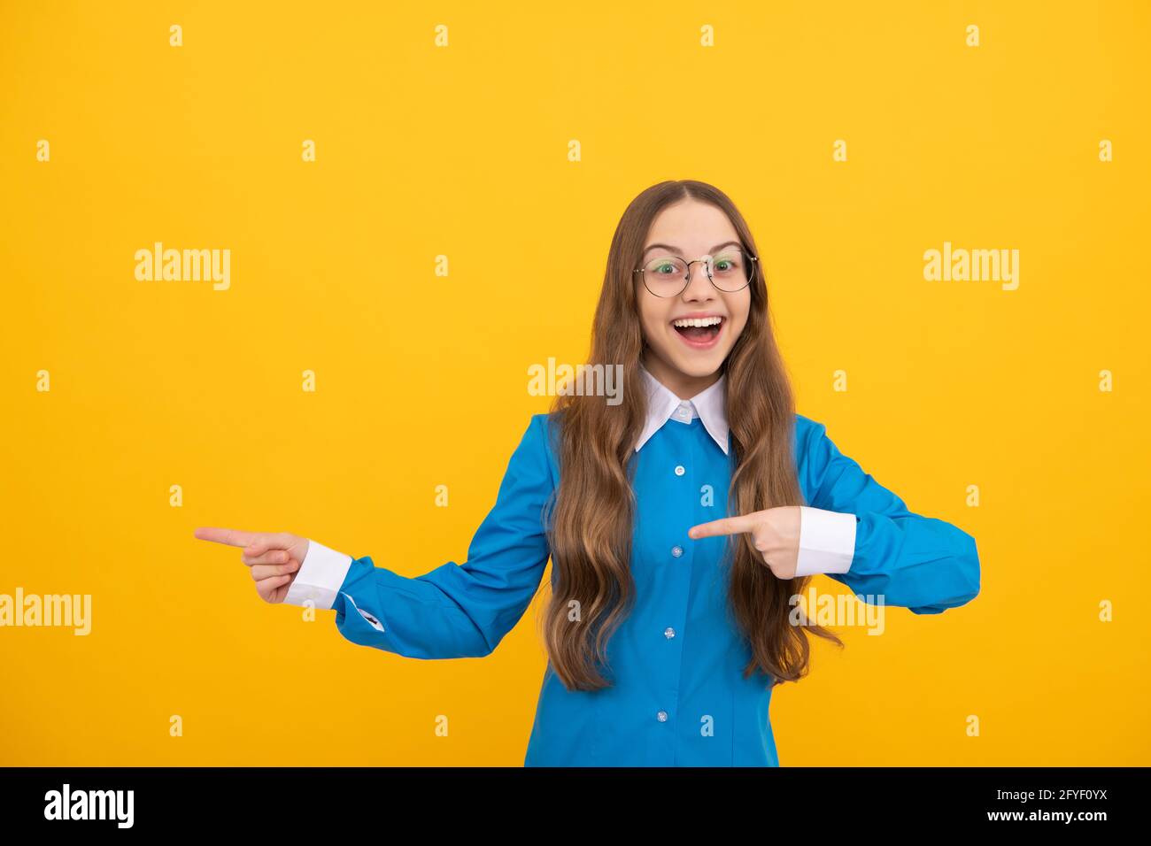 Glücklich zurück zur Schule Mädchen Lächeln zeigt Finger gelb Hintergrund Kopie Raum, Verkauf Stockfoto