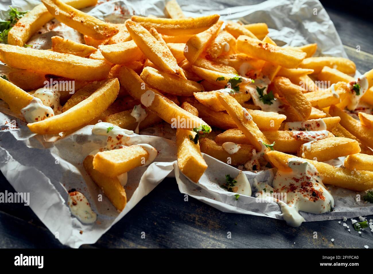 Von oben appetitlich knusprige frische Pommes frites garniert mit Mayo und Kräuter und auf Gewebe serviert Stockfoto