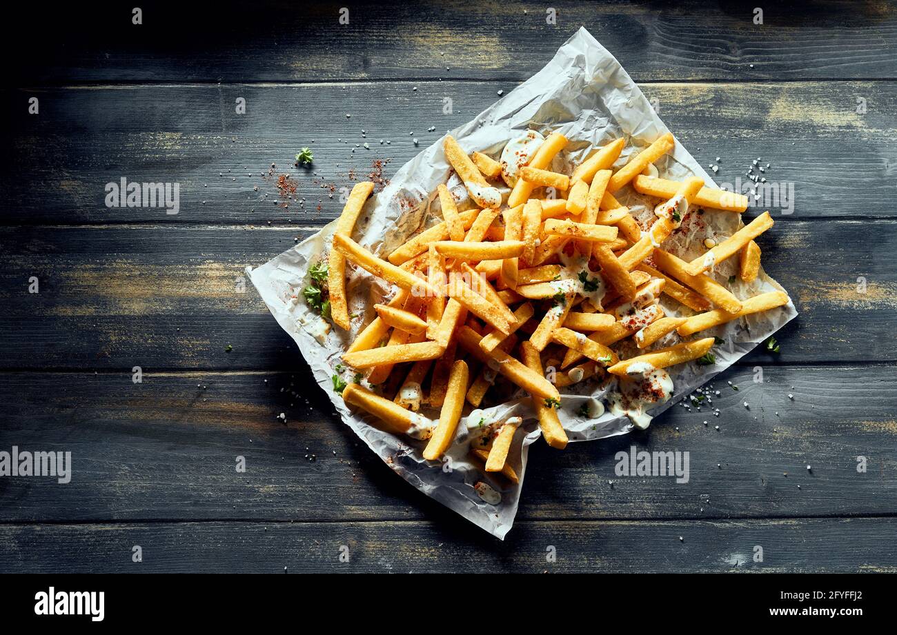 Draufsicht Frische appetitlich knusprige Pommes frites auf weißem Beutel gehäuft Auf Holztisch Stockfoto
