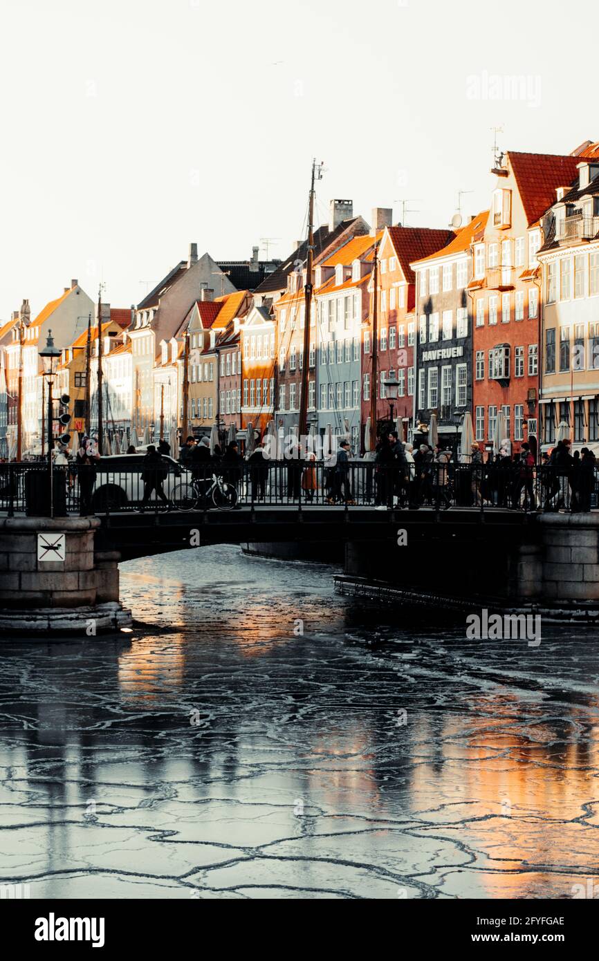 Gefrorenes Wasser am Nyhavn-Kanal, mit Menschen, die über eine Brücke gehen. Stockfoto