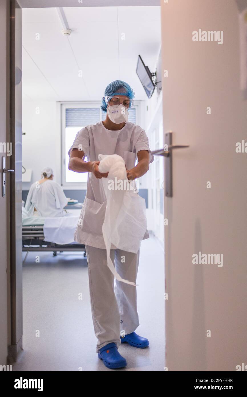 Krankenschwester, die beim Verlassen eines Zimmers ihr Kleid ausnimmt, Covid-Krankenhausaufenthaltseinheit der CHU de Limoges. Stockfoto