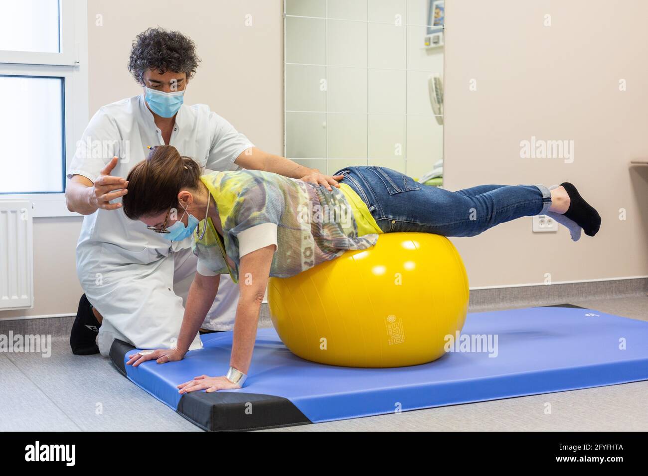Muskelstärkung mit einem Physiotherapeuten zur Linderung von Schmerzen im unteren Rücken mit einem Reha-Ball (Swiss Ball). Krankenhaus Limoges, Frankreich. Stockfoto