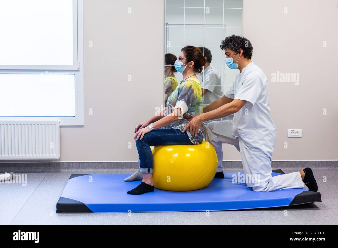 Muskelstärkung mit einem Physiotherapeuten zur Linderung von Schmerzen im unteren Rücken mit einem Reha-Ball (Swiss Ball). Krankenhaus Limoges, Frankreich. Stockfoto