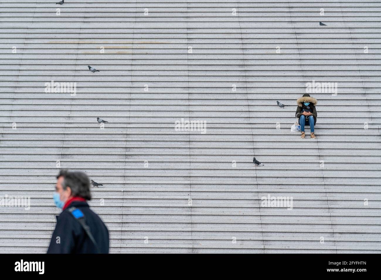 Person, die während einer Pandemie allein auf einer Treppe sitzt. Stockfoto
